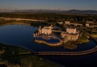 Clube principal do Condomínio Costa Serena, com design moderno, piscina e deck sobre o lago, sob a luz dourada do entardecer.
