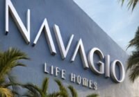 Fachada moderna do Condomínio Navagio Life Homes em Capão da Canoa, com letras 3D brancas sobre parede azul texturizada, e...