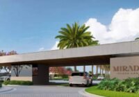 Entrada principal do Mirador Playa Arenas - Capão Novo, destacando arquitetura contemporânea, palmeiras e segurança para m...