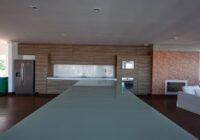 Cozinha gourmet com ilha, armários amadeirados, eletrodomésticos inox e lareira, no Condomínio Rossi Atlântida.