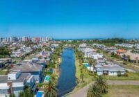 Condomínio Villaggio Atlântida - Xangri-lá em vista aérea, com canal, casas de alto padrão, piscinas e o mar ao fundo, sob...